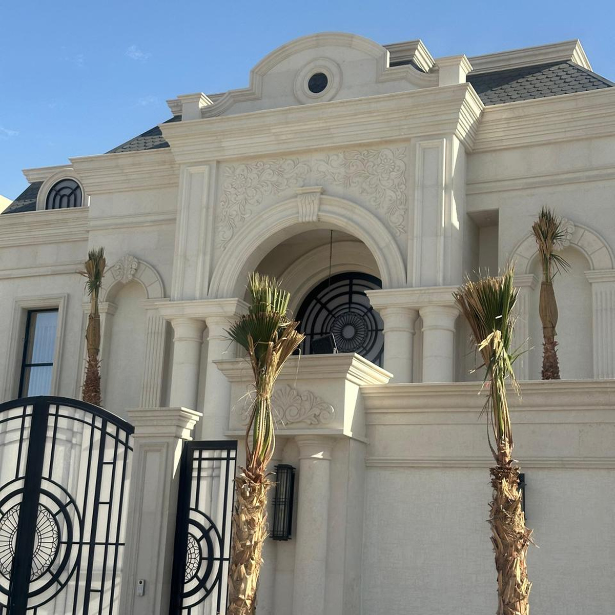 مدخل قصر فخم بباب رئيسي وأعمدة حجرية وأشجار نخيل في الرياض